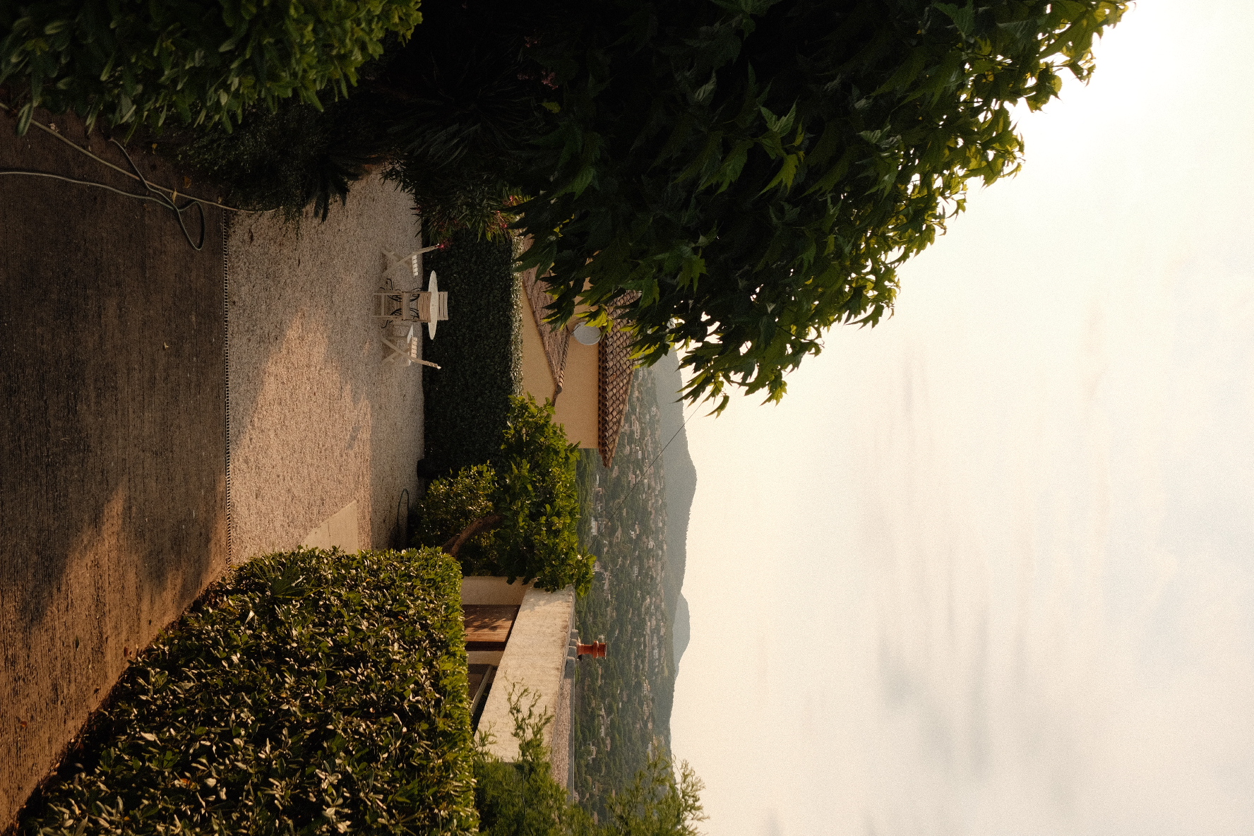 Gravel courtyard at dusk overlooking a coastline and hills