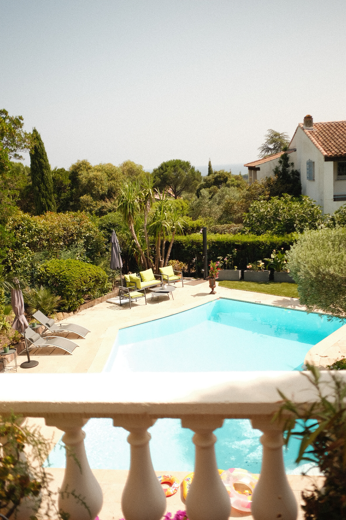 Pool and sun loungers seen over a stone balustrade at a coastal villa